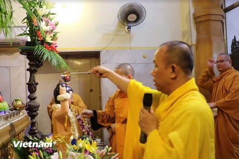 Thượng tọa Thích Hạnh Chánh cử hành nghi lễ tắm Phật. (Ảnh: Huy Bình/Vietnam+)