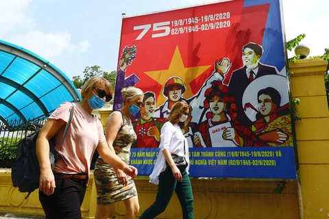 Du khách quốc tế đeo khẩu trang, dạo bộ trên phố Điện Biên Phủ. (Ảnh: Lâm Khánh/TTXVN)