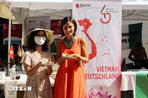 Phó Thị trưởng thành phố Augsburg, bà Martina Wild (áo dài cam), ấn tượng với ẩm thực của Việt Nam. (Ảnh: TTXVN phát)
