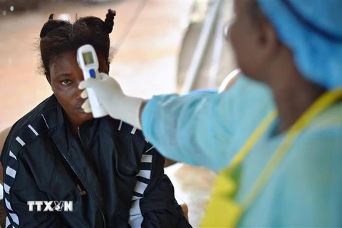 Nhân viên y tế kiểm tra thân nhiệt bệnh nhân nghi nhiễm virus Ebola tại Kenema, Guinea, ngày 16/8/2014. (Ảnh: AFP/TTXVN)