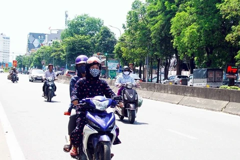 Người dân trang bị khẩu trang và mặc áo chống nắng kín khi di chuyển trên đường trong thời tiết nắng nóng. (Ảnh: Tá Chuyên/TTXVN)