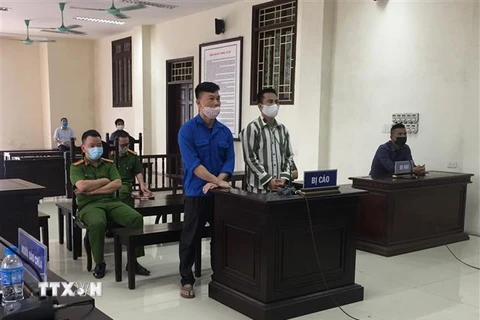 Bị cáo Vũ Đình Kiên (áo xanh, bên trái) và bị cáo Phạm Văn Úy và tại phiên tòa. (Ảnh: TTXVN phát)