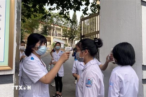 Các thí sinh tại điểm thi Trường Trung học phổ thông Bãi Cháy, thành phố Hạ Long được đo thân nhiệt, sát khuẩn tay ngay ở cổng trường. (Ảnh: TTXVN)