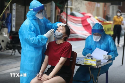 Nhân viên y tế lấy mẫu cho người dân trong khu vực phong tỏa tạm thời ở phố Hàng Mắm (phường Lý Thái Tổ) do liên quan đến trường hợp dương tính với SARS-CoV-2.(Ảnh: Minh Quyết/TTXVN)