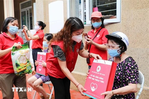 Phó Chủ tịch Hội Chữ thập Đỏ thành phố Hà Nội Đinh Thị Phức trao túi hàng gia đình tới người dân bị ảnh hưởng bởi dịch bệnh COVID-19 đang sống tại quận Thanh Xuân trong sáng 15/8. (Ảnh: Thanh Tùng/TTXVN)