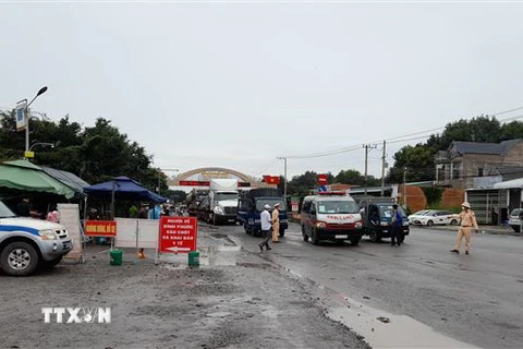 Lực lượng chức năng điều phối giao thông, hướng dẫn người dân vào làm thủ tục tại chốt Tân Lập, huyện Đồng Phú tỉnh Bình Phước sáng 17/10. (Ảnh: Sỹ Tuyên/TTXVN)