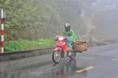 Người dân đi xe máy vận chuyển hàng hóa trong sương sớm, giá lạnh trên đỉnh đèo Pha Đin, Điện Biên. (Ảnh: Xuân Tiến/TTXVN)