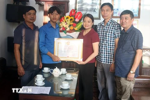 Lãnh đạo Ủy ban Nhân dân huyện Hải Hậu trao Giấy khen cho em Bùi Hải An (thứ 2, từ trái sang). (Ảnh: TTXVN phát)