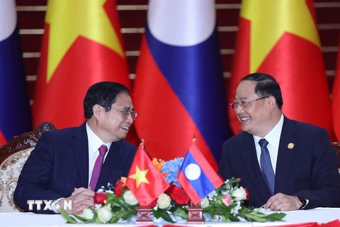 Thủ tướng Phạm Minh Chính và Thủ tướng Lào Sonexay Siphandone trao đổi tại lễ ký các văn kiện hợp tác giữa hai nước Việt Nam-Lào. (Ảnh: Dương Giang/TTXVN)