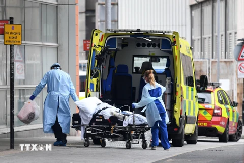 Nhân viên y tế chuyển bệnh nhân nhiễm COVID-19 vào bệnh viện Hoàng gia London, Anh. (Ảnh: AFP/TTXVN)