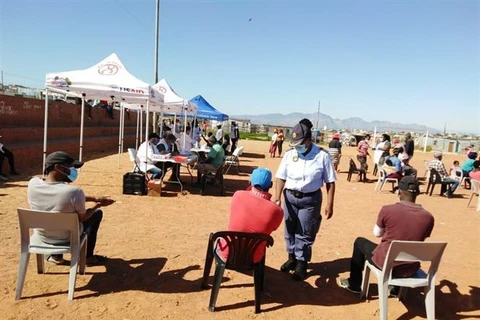 Cảnh sát nhắc nhở người dân thực hiện giãn cách xã hội trong khi chờ đợi đến lượt tại một điểm xét nghiệm COVID-19. (Ảnh: Phi Hùng/TTXVN)