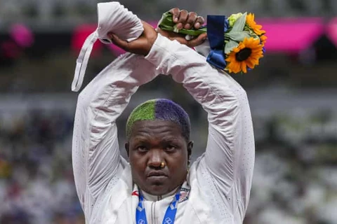 Nữ VĐV người Mỹ gốc Phi đã đan hay cánh tay chéo nhau thành hình dấu “X” khi lên bục nhận Huy chương bạc nội dung ném bóng.(Nguồn: TheGuardian)