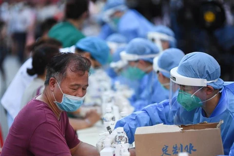 Nhân viên y tế lấy mẫu xét nghiệm COVID-19 cho người dân tại tỉnh Quảng Đông (Trung Quốc). (Ảnh: THX/TTXVN)