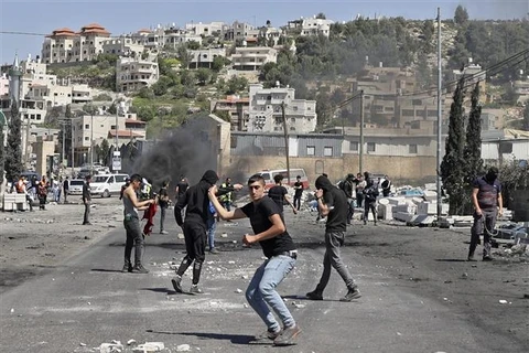 Người biểu tình Palestine ném đá về phía cảnh sát Israel trong cuộc đụng độ tại khu vực Đền Al-Aqsa ở Đông Jerusalem ngày 15/4/2022. (Ảnh: AFP/TTXVN)