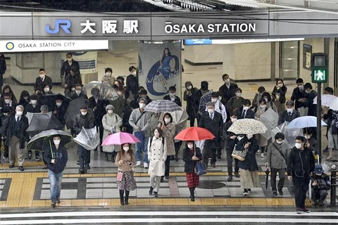 Người dân đeo khẩu trang phòng dịch COVID-19 khi đi trên đường phố ở Osaka (Nhật Bản), ngày 22/3/2022. (Ảnh: Kyodo/TTXVN)