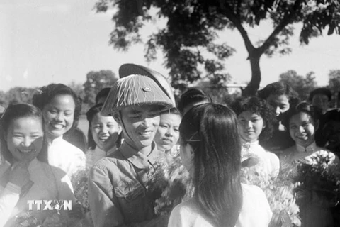 Thiếu tướng Vương Thừa Vũ, Tư lệnh Đại đoàn 308, Chủ tịch Ủy ban Quân chính Thành phố giữa vòng vây của các nữ sinh trường Trưng Vương tặng hoa chúc mừng bên hồ Hoàn Kiếm trong ngày giải phóng Thủ đô. (Ảnh: Tư liệu TTXVN)