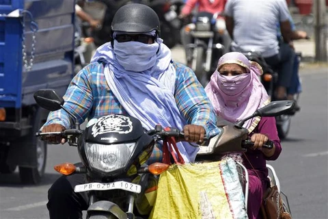 Người đi đường trùm khăn tránh nắng nóng ở Amritsar (Ấn Độ). (Ảnh: AFP/TTXVN)