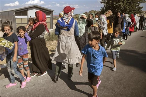 Người di cư xếp hàng chờ nhận thực phẩm cứu trợ tại Đảo Lesbos (Hy Lạp). (Ảnh: AFP/TTXVN)