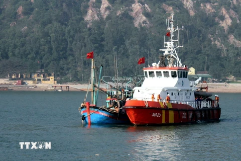 Tàu SAR 273 của Trung tâm Phối hợp tìm kiếm cứu nạn hàng hải Việt Nam (màu vàng) đang lai dắt tàu NA 93018 TS (màu xanh) vào bờ. (Ảnh: Tá Chuyên/TTXVN)