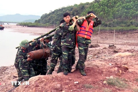 Lực lượng chức năng xử lý di chuyển quả bom đến nơi an toàn. (Ảnh: Nguyễn Hoàng/TTXVN)