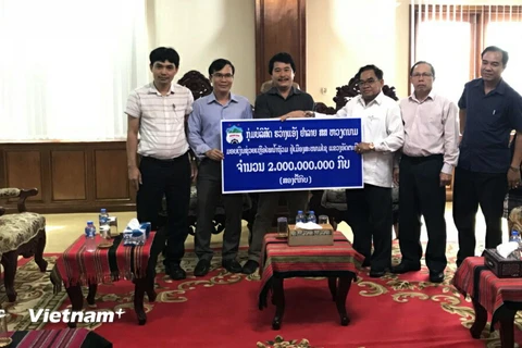 Đại diện Tập đoàn HAGL đang trao tượng trưng số tiền 2 tỷ kip (trên 200.000 USD) cho đại diện tỉnh Atappeu. (Ảnh: CTV/Vietnam+)