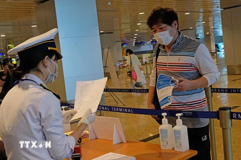 Lực lượng chức năng kiểm tra khai báo y tế của những hành khách đáp chuyến bay từ Hàn Quốc đến sân bay Cam Ranh trong chiều 25/2. (Ảnh: Nguyễn Dũng/TTXVN)