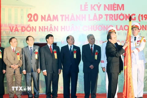 Thủ tướng Nguyễn Xuân Phúc gắn Huân chương Lao động hạng Nhất lên Cờ truyền thống của Trường Đại học Kinh doanh và Công nghệ Hà Nội. (Ảnh: Thống Nhất/TTXVN)