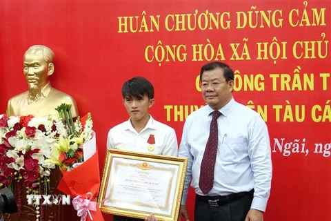 Phó chủ tịch UBND tỉnh Quảng Ngãi Nguyễn Tăng Bính trao Huân chương Dũng cảm cho ngư dân Trần Thanh Ron. (Ảnh: Phước Ngọc/TTXVN)