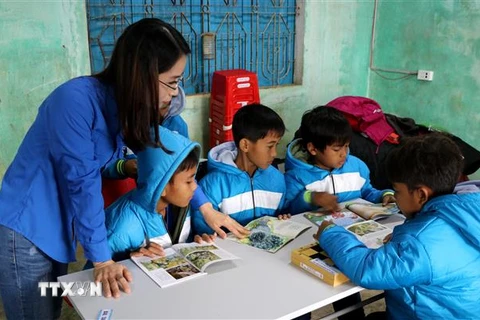 Thanh niên TTXVN cùng các em học sinh đọc những cuốn sách trong "Tủ sách Đinh Hữu Dư". (Ảnh: Nguyên Lý/TTXVN)