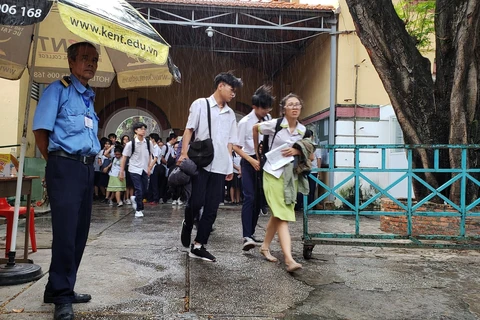 Mưa lớn khiến thí sinh gặp khó khăn khi rời khỏi điểm thi tại Hội đồng thi Trường THPT Marie Curie, Quận 3, Thành phố Hồ Chí Minh. (Ảnh: Xuân Dự/TTXVN)
