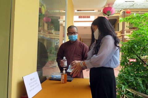 Sư thầy chùa Anh Vinh (thành phố Tuyên Quang) hướng dẫn người dân thực hiện rửa tay trước khi vào lễ chùa. (Ảnh Quang Đán/TTXVN)