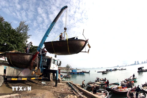 Xe cần cẩu đưa các phương tiện đánh bắt thủy sản của ngư dân Đà Nẵng lên bờ, vận chuyển vào sâu đất liền để tránh bão số 9. (Ảnh: Trần Lê Lâm/TTXVN)