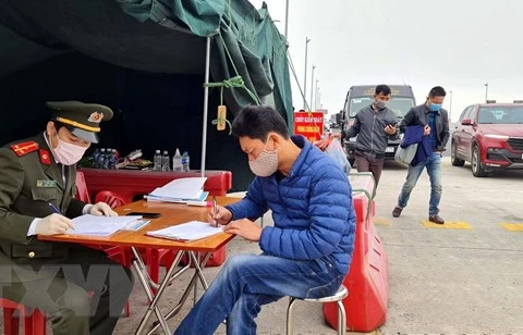 Lực lượng chức năng làm nhiệm vụ hướng dẫn, phân luồng giao thông, khai báo y tế tại chốt trạm cầu Bạch Đằng, thị xã Quảng Yên. (Ảnh: TTXVN)