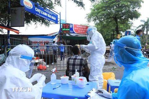 Lấy mẫu xét nghiệm SARS-CoV-2 các tiểu thương bán hàng trong chợ Xanh Văn Quán, Hà Nội, nơi ca bệnh COVID-19 từng đến mua sắm. (Ảnh: Phan Tuấn Anh/TTXVN)