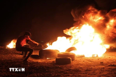 Người biểu tình Palestine đốt cháy lốp xe trong cuộc đụng độ với binh sỹ Israel tại Dải Gaza, ngày 28/8. (Ảnh: THX/TTXVN)