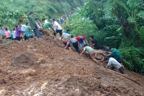 Người dân hỗ trợ đưa xe máy của chị Lò Thị Châu (ở tỉnh Lai Châu) từ dưới vực lên. (Ảnh: TTXVN phát)
