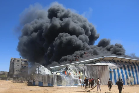 Lính cứu hoả nỗ lực dập lửa căn nhà bị trúng oanh kích của máy bay Israel tại thành phố Rafah, Dải Gaza ngày 18/5/2021. (Ảnh: THX/TTXVN)
