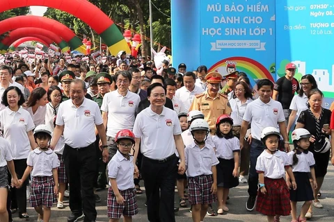 Lãnh đạo Chính phủ và các Bộ, ban ngành đi bộ kêu gọi toàn dân đội mũ bảo hiểm cho trẻ em khi tham giao giao thông. (Ảnh: Việt Hùng/Vietnam+)