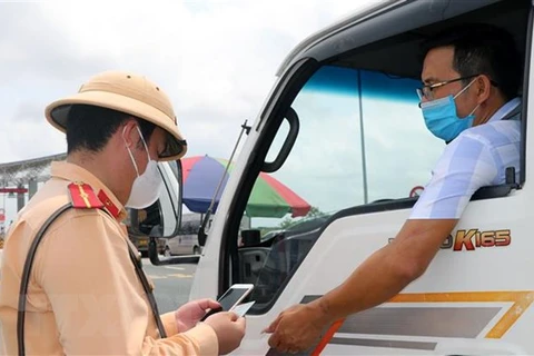 Cảnh sát giao thông kiểm tra giấy tờ của một phương tiện chở hàng hóa ngay tại chốt kiểm soát dịch COVID-19. (Ảnh: Minh Sơn/Vietnam+)