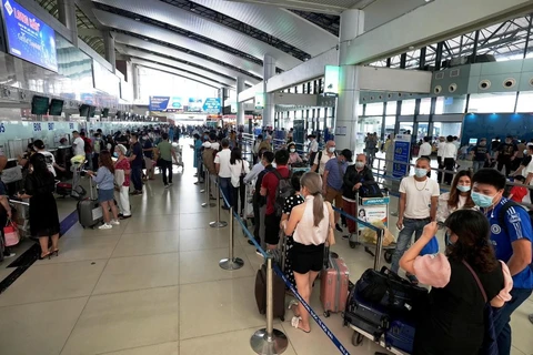 Hành khách xếp hàng dài làm thủ tục để lên chuyến bay. (Ảnh: CTV/Vietnam+)
