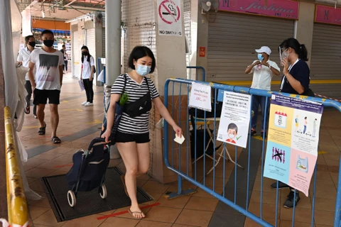 Người dân đeo khẩu trang và thực hiện giãn cách xã hội phòng lây nhiễm dịch COVID-19 tại một chợ ở Singapore, ngày 22/4/2020. (Ảnh: AFP/TTXVN)