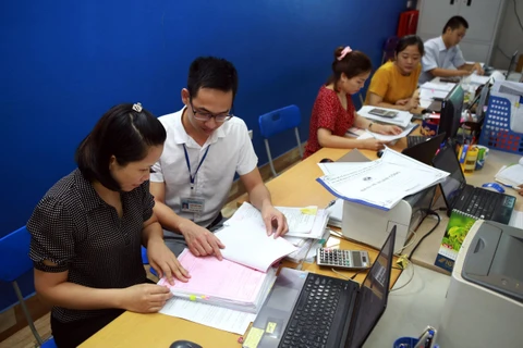 Cán bộ thuế tỉnh Thái Nguyên hướng dẫn doanh nghiệp Công ty CP TM Thép Việt Cường khai báo thủ tục giãn thuế. (Ảnh: Danh Lam/TTXVN)