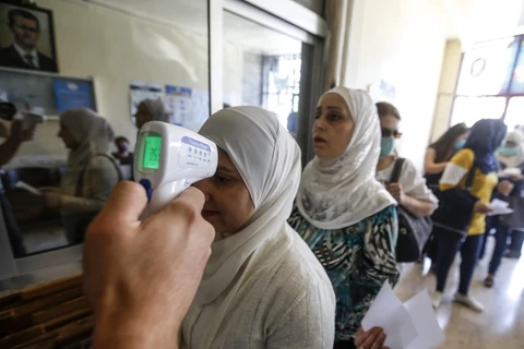 Kiểm tra thân nhiệt phòng lây nhiễm COVID-19 tại một điểm bầu cử ở Damascus, ngày 19/7/2020. (Ảnh: AFP/TTXVN)