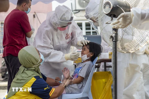 Nhân viên y tế lấy mẫu xét nghiệm COVID-19 cho trẻ em tại Selangor, Malaysia,, ngày 14/8/2021. (Ảnh: THX/TTXVN)