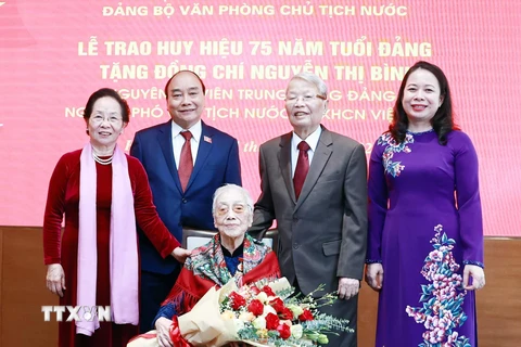 Chủ tịch nước Nguyễn Xuân Phúc và các đại biểu tại Lễ trao tặng huy hiệu 75 năm tuổi Đảng cho bà Nguyễn Thị Bình, nguyên Ủy viên Trung ương Đảng, nguyên Phó Chủ tịch nước CHXHCN Việt Nam. (Ảnh: Thống Nhất/TTXVN)