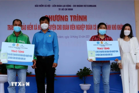  Lãnh đạo Liên đoàn Lao động quận Tân Phú, TP Hồ Chí Minh trao sổ bảo hiểm cho đoàn viên nghiệp đoàn có hoàn cảnh khó khăn. (Ảnh: Thanh Vũ/TTXVN)