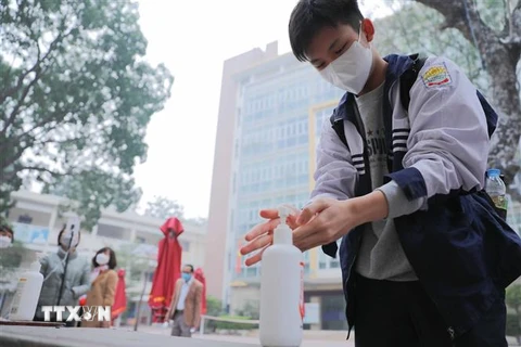 Học sinh lớp 12 trường THPT Kim Liên, quận Đống Đa thực hiện sát khuẩn tay khi tới trường học trực tiếp từ sáng 4/1/2022. (Ảnh: Thanh Tùng/TTXVN)