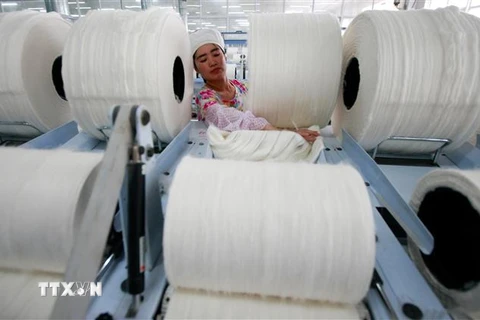 Công nhân làm việc trong một nhà máy sợi ở tỉnh An Huy, Trung Quốc. (Ảnh: AFP/TTXVN)