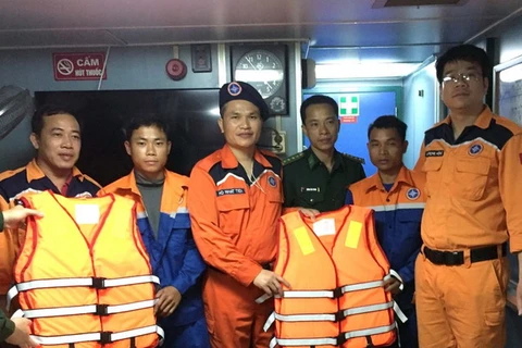 Lực lượng cứu nạn cùng hai ngư dân gặp nạn. (Ảnh: Trần Hoàng Ngọc/TTXVN)