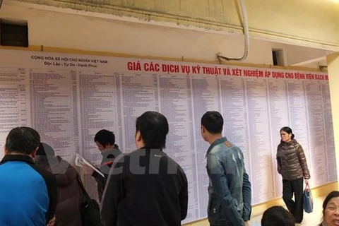 Người dân xem bảng giá viện phí tại bệnh viện Bạch Mai. (Ảnh: PV/Vietnam+)